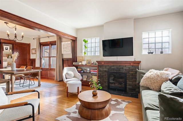 living room featuring a notable chandelier, a fireplace, and light wood-type flooring