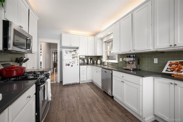 kitchen with sink, white cabinetry, dark hardwood / wood-style flooring, stainless steel appliances, and backsplash