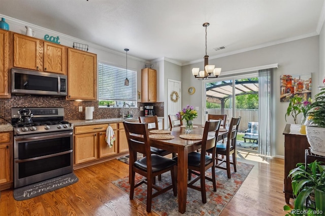 2670 E 136th Pl, Thornton, CO 80602 - dining room with light wood-style floors, a chandelier, and ornamental molding
