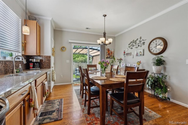 2670 E 136th Pl, Thornton, CO 80602 - dining space with light wood finished floors, plenty of natural light, a chandelier, crown molding, and baseboards