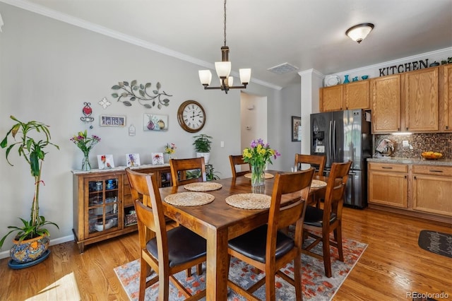 2670 E 136th Pl, Thornton, CO 80602 - dining room featuring crown molding, light wood-style floors, a chandelier, baseboards, and decorative columns
