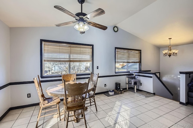 dining area featuring ceiling fan with notable chandelier, lofted ceiling, and light tile patterned floors