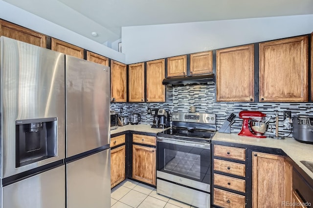 kitchen with tasteful backsplash, light tile patterned floors, vaulted ceiling, and stainless steel appliances