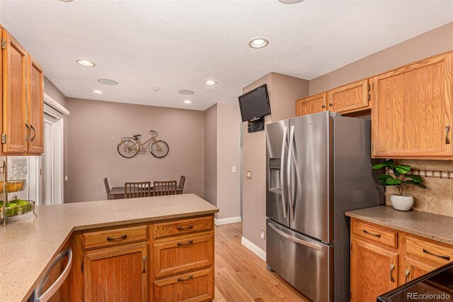 8588 S Woody Way, Highlands Ranch, CO 80126 - kitchen with appliances with stainless steel finishes, a peninsula, light wood-style floors, tasteful backsplash, and recessed lighting
