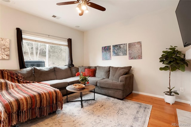 living area with visible vents, ceiling fan, baseboards, and wood finished floors