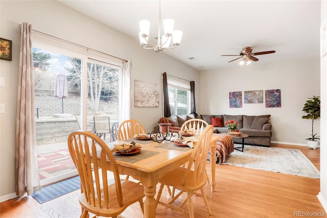 dining area with ceiling fan with notable chandelier, light wood-type flooring, and baseboards