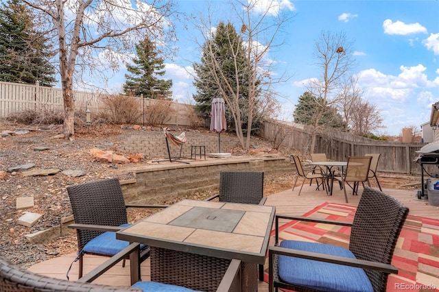 view of patio featuring outdoor dining space, a fenced backyard, and a deck