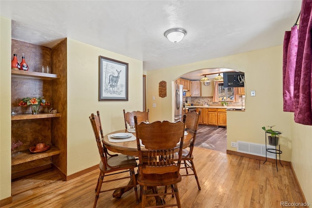 9061 N Rex Ln, Conifer, CO 80433 - dining space featuring arched walkways, light wood-type flooring, and baseboards