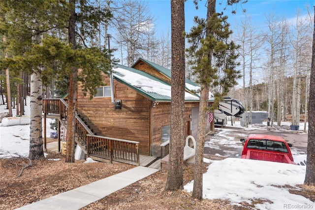 9061 N Rex Ln, Conifer, CO 80433 - snow covered property with metal roof and stairs