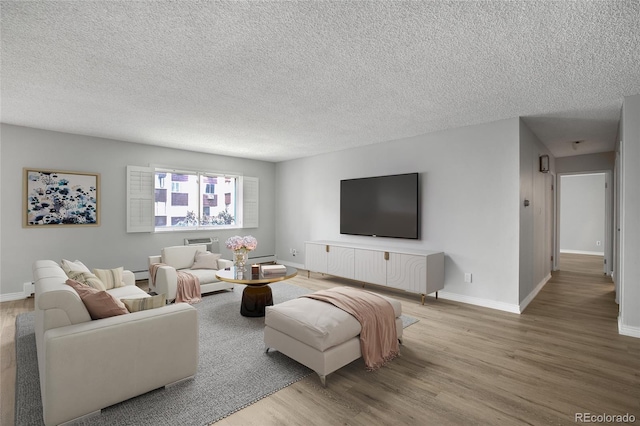 living room with baseboard heating, a textured ceiling, and hardwood / wood-style flooring