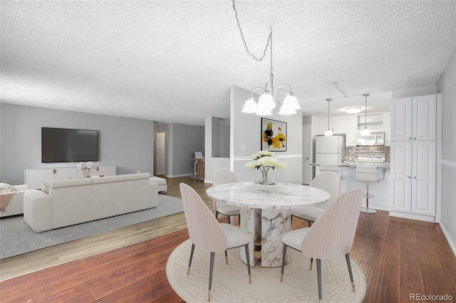 dining space featuring an inviting chandelier, a textured ceiling, and hardwood / wood-style floors