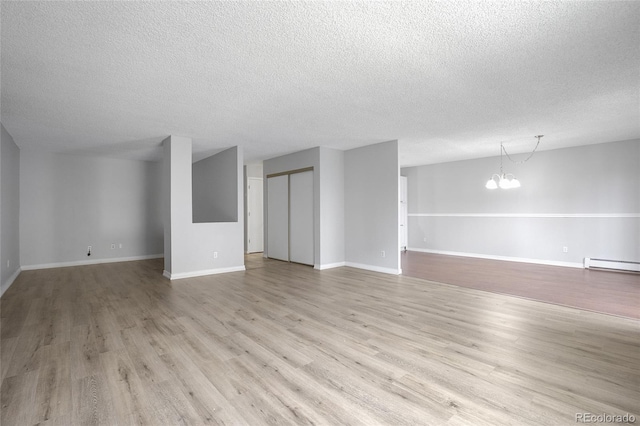 unfurnished living room featuring light hardwood / wood-style floors, an inviting chandelier, a textured ceiling, and a baseboard heating unit