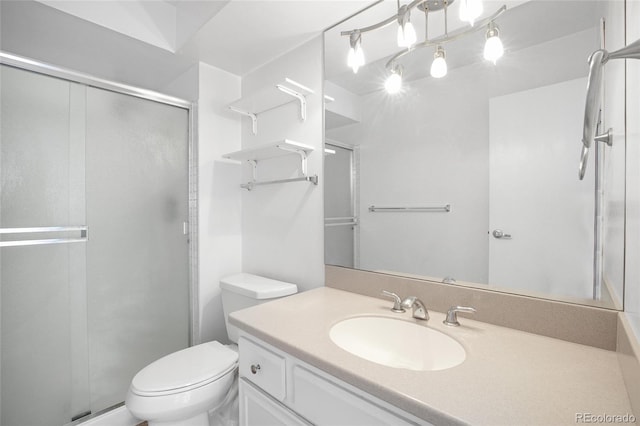 bathroom with a shower with shower door, vanity, and toilet