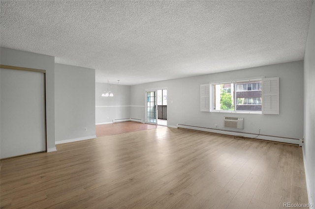 empty room featuring hardwood / wood-style flooring, a textured ceiling, a notable chandelier, and baseboard heating