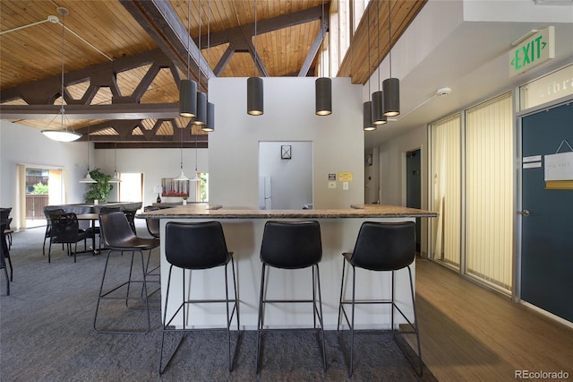 kitchen featuring decorative light fixtures, hardwood / wood-style flooring, wooden ceiling, high vaulted ceiling, and beamed ceiling