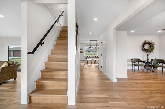stairs with wood finished floors, recessed lighting, and baseboards