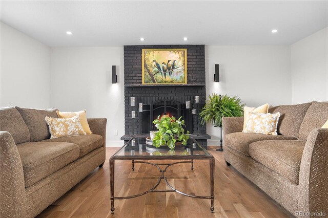 living room with wood finished floors, recessed lighting, a brick fireplace, and baseboards