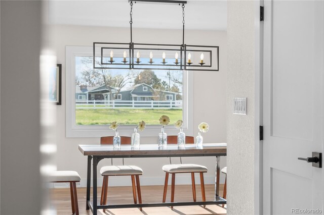 dining space with a chandelier, wood finished floors, and healthy amount of natural light