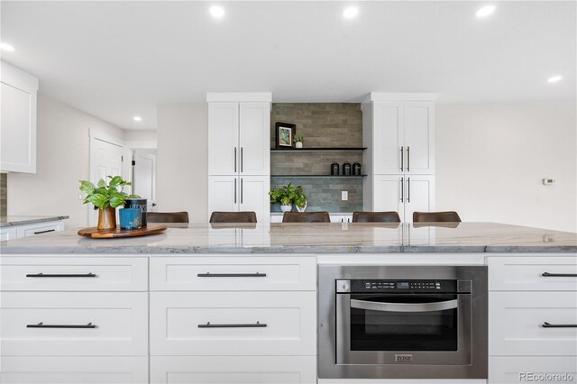 kitchen with recessed lighting, white cabinetry, light stone counters, and tasteful backsplash