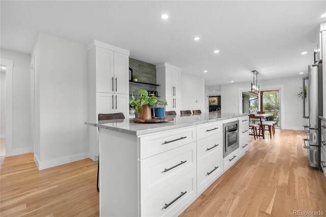 kitchen featuring a kitchen island, light wood-style flooring, white cabinets, baseboards, and recessed lighting
