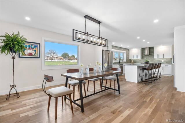 dining space with light wood finished floors, recessed lighting, a chandelier, and baseboards