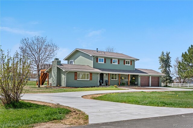 traditional home with an attached garage, driveway, a chimney, and a porch