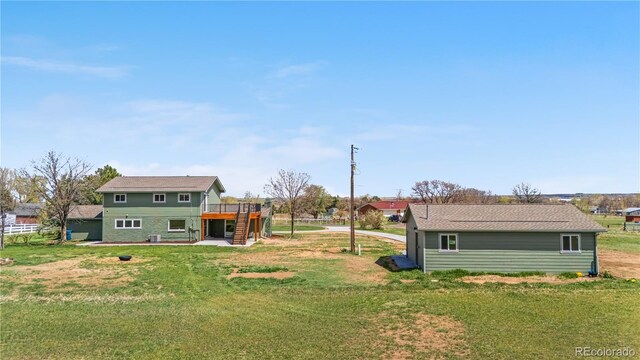 view of green lawn featuring a deck and stairs