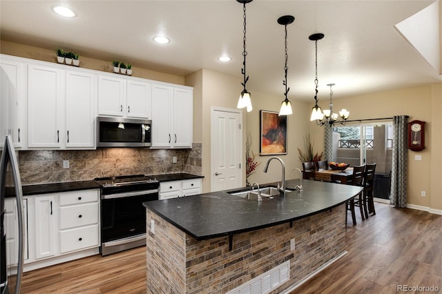 kitchen with pendant lighting, sink, appliances with stainless steel finishes, an island with sink, and white cabinets