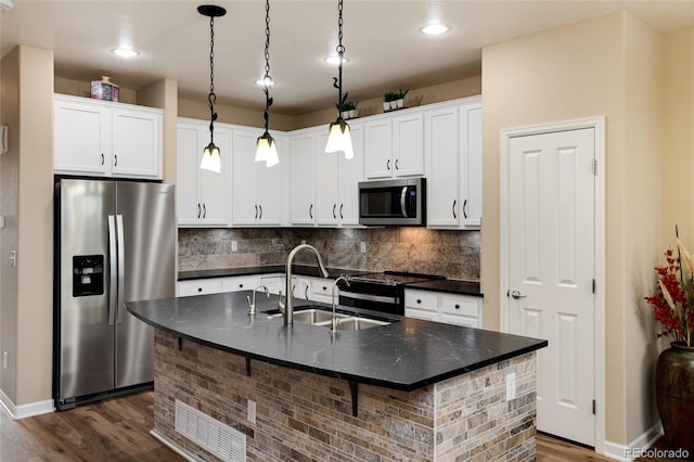 kitchen with dark wood-type flooring, sink, a center island with sink, pendant lighting, and stainless steel appliances