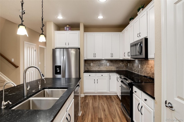 kitchen featuring sink, white cabinetry, backsplash, stainless steel appliances, and decorative light fixtures