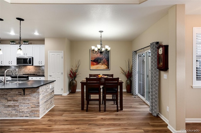 dining space featuring sink, hardwood / wood-style floors, and a chandelier