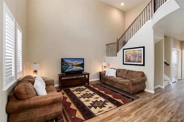 living room with wood-type flooring and a towering ceiling