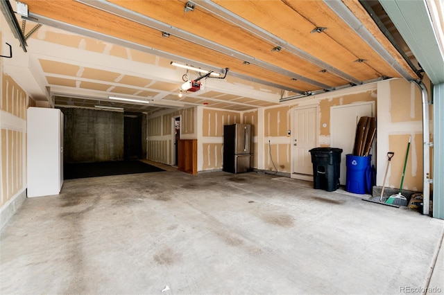 garage with a garage door opener and stainless steel refrigerator