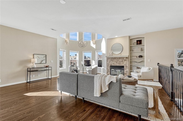 living room with built in shelves, dark wood-type flooring, and a notable chandelier