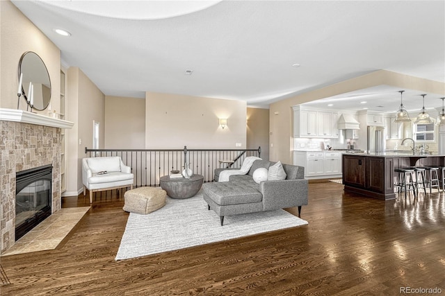 living room featuring dark hardwood / wood-style flooring, sink, and a tile fireplace