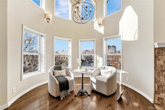 living area featuring hardwood / wood-style flooring, a high ceiling, and a chandelier