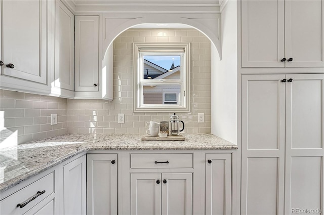 kitchen with decorative backsplash, light stone counters, and white cabinetry