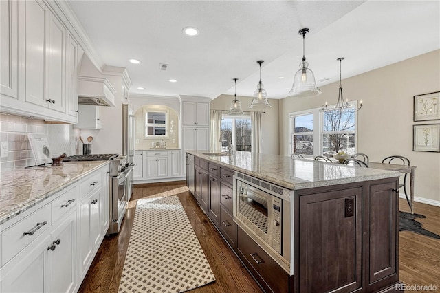 kitchen with hanging light fixtures, tasteful backsplash, a large island, white cabinetry, and stainless steel appliances