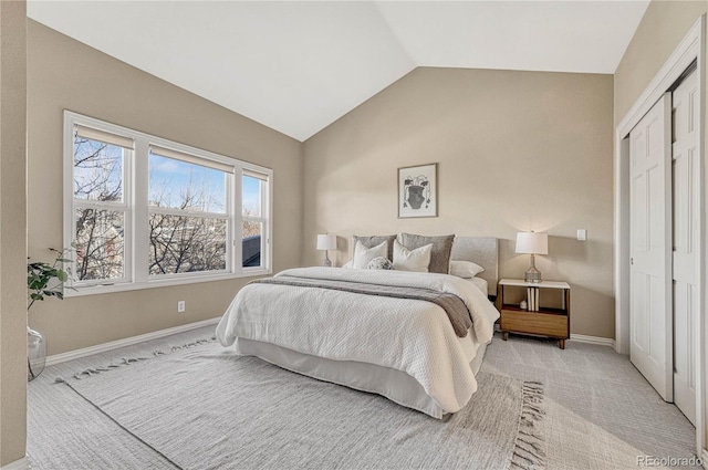 bedroom featuring light carpet, a closet, and lofted ceiling