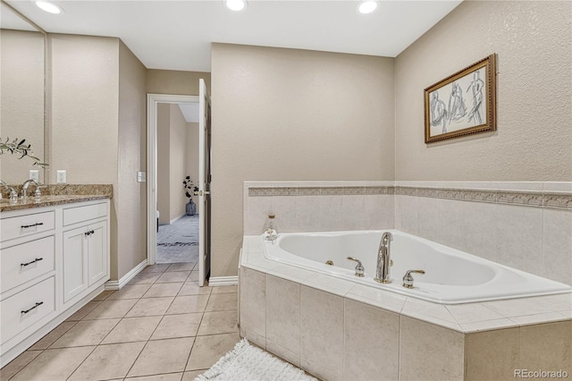 bathroom with tile patterned flooring, vanity, and tiled bath