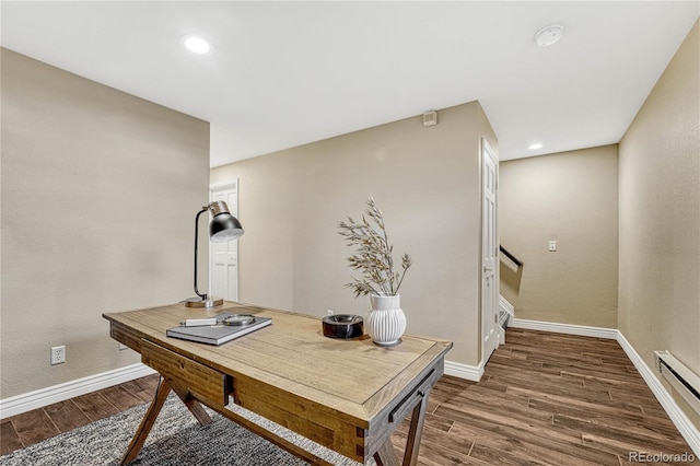 office space with dark wood-type flooring and a baseboard heating unit