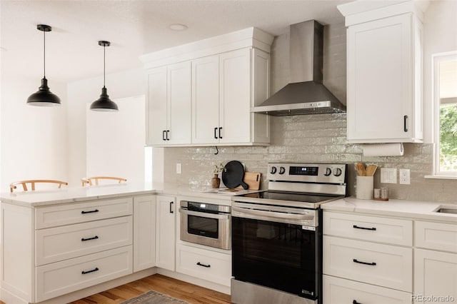 2263 Yellowstone St, Golden, CO 80401 - kitchen featuring wall chimney exhaust hood, appliances with stainless steel finishes, a peninsula, backsplash, and white cabinets