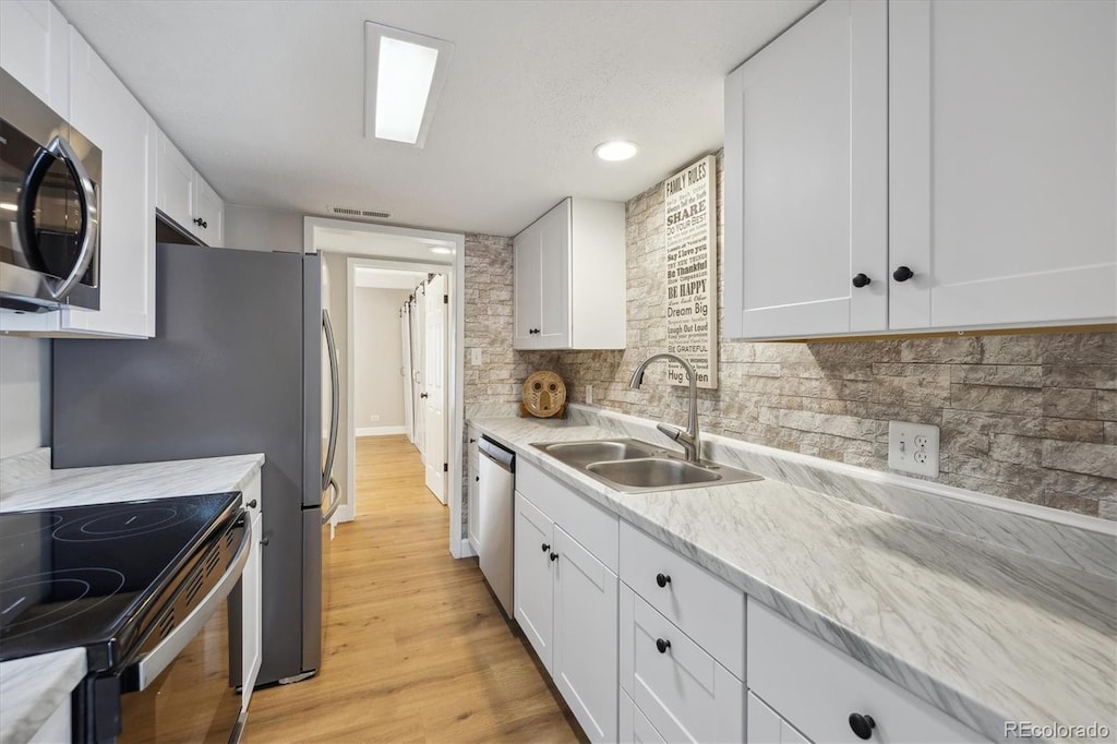 9700 E Iliff Ave Unit 81, Denver, CO 80231 - kitchen featuring a sink, white cabinetry, decorative backsplash, and appliances with stainless steel finishes