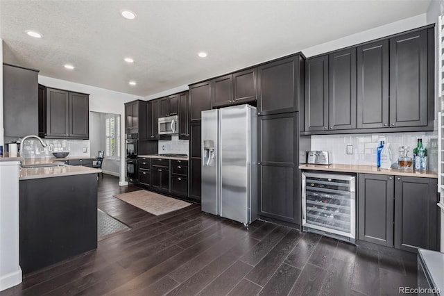 kitchen featuring decorative backsplash, appliances with stainless steel finishes, wine cooler, and sink