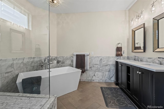 bathroom featuring a tub to relax in, vanity, and tile walls