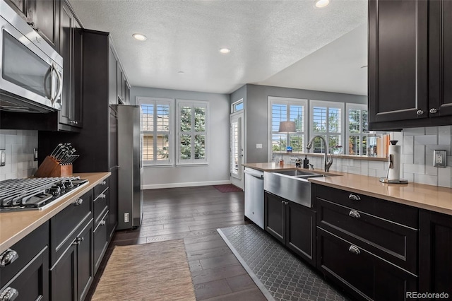 kitchen with appliances with stainless steel finishes, dark hardwood / wood-style flooring, tasteful backsplash, and a textured ceiling