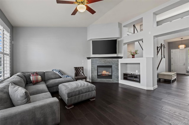 living room featuring built in shelves, ceiling fan, dark hardwood / wood-style flooring, and a stone fireplace