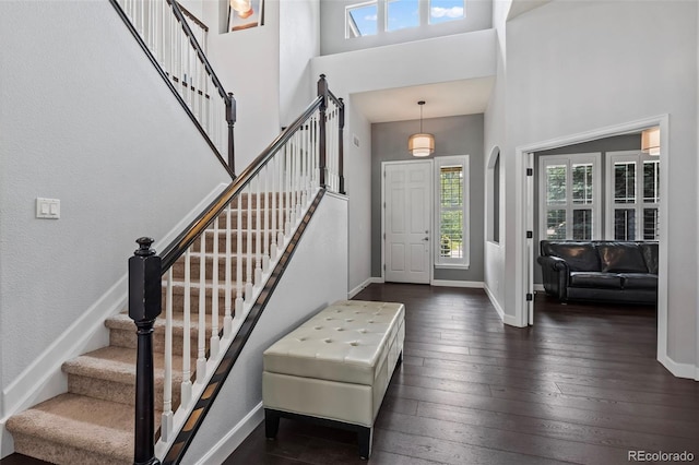 foyer entrance with a towering ceiling and dark hardwood / wood-style floors