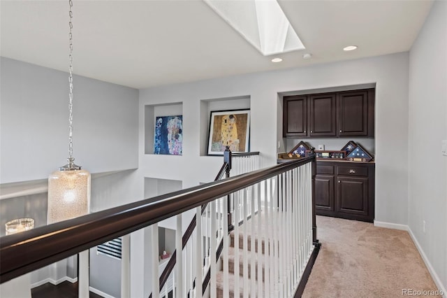 hall featuring light colored carpet and a skylight