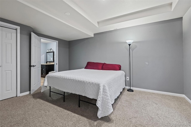 bedroom with carpet, connected bathroom, and a raised ceiling